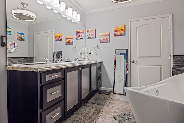 902 51st St, Galveston, TX 77551 - bathroom with crown molding, a freestanding bath, wood finished floors, and vanity