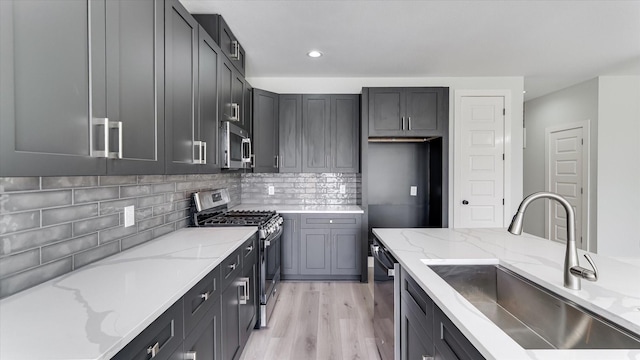 6902 Apollo St, Houston, TX 77091 - kitchen with stainless steel appliances, light stone counters, light wood-style floors, decorative backsplash, and recessed lighting