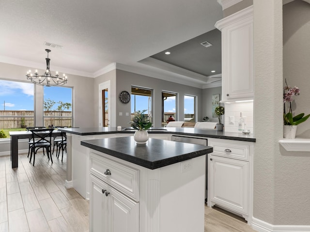 103 Lakeshore Ct, Clute, TX 77531 - kitchen featuring dark countertops, a chandelier, a center island, white cabinetry, and hanging light fixtures