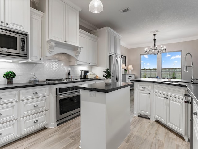103 Lakeshore Ct, Clute, TX 77531 - kitchen featuring appliances with stainless steel finishes, dark countertops, white cabinets, a chandelier, and decorative backsplash