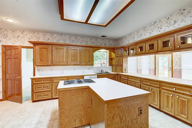 3134 Lake Island Dr, Montgomery, TX 77356 - kitchen with wallpapered walls, light countertops, a center island, stovetop with downdraft, and brown cabinetry