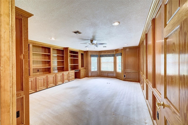 3134 Lake Island Dr, Montgomery, TX 77356 - unfurnished living room featuring a textured ceiling, a ceiling fan, built in shelves, light colored carpet, and ornamental molding