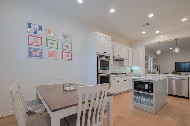 14439 Basalt Ln, Houston, TX 77077 - kitchen featuring appliances with stainless steel finishes, crown molding, light countertops, light wood-type flooring, and white cabinetry