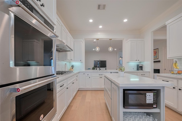14439 Basalt Ln, Houston, TX 77077 - kitchen with appliances with stainless steel finishes, white cabinetry, light wood finished floors, backsplash, and hanging light fixtures