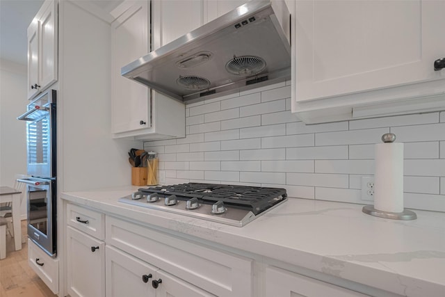 14439 Basalt Ln, Houston, TX 77077 - kitchen with ventilation hood, stainless steel appliances, white cabinetry, and tasteful backsplash