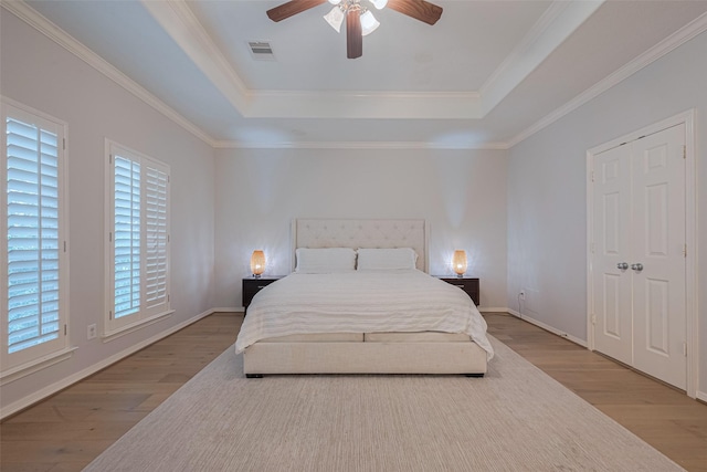 14439 Basalt Ln, Houston, TX 77077 - bedroom featuring a tray ceiling, wood finished floors, ornamental molding, and a ceiling fan