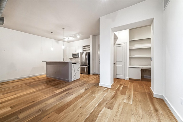 1901 Post Oak Blvd Unit 1206, Houston, TX 77056 - kitchen with appliances with stainless steel finishes, light wood finished floors, white cabinets, light countertops, and a kitchen island with sink
