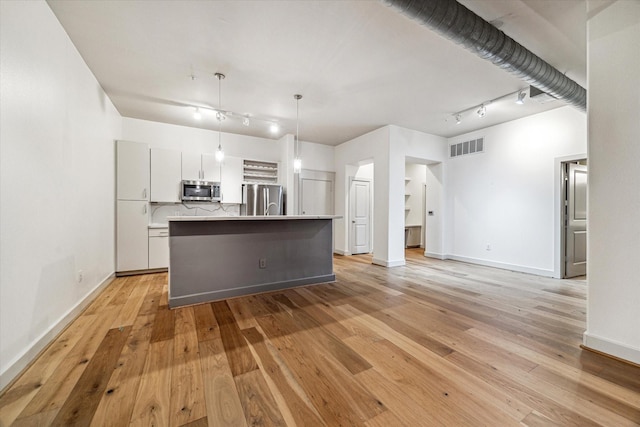 1901 Post Oak Blvd Unit 1206, Houston, TX 77056 - kitchen featuring appliances with stainless steel finishes, track lighting, an island with sink, light wood-type flooring, and hanging light fixtures