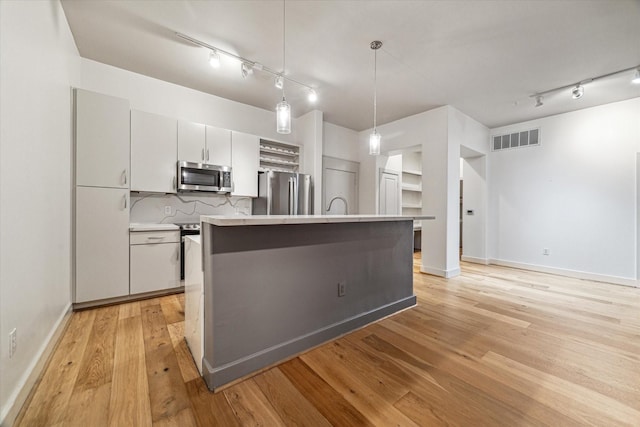 1901 Post Oak Blvd Unit 1206, Houston, TX 77056 - kitchen featuring stainless steel appliances, rail lighting, light countertops, hanging light fixtures, and an island with sink