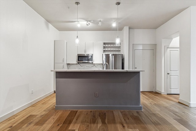 1901 Post Oak Blvd Unit 1206, Houston, TX 77056 - kitchen with stainless steel appliances, white cabinets, an island with sink, and light wood finished floors