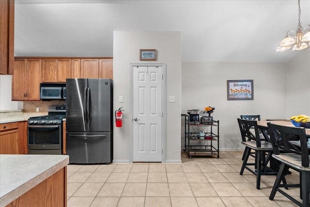 1803 Winding Trail Ln, Alvin, TX 77511 - kitchen with appliances with stainless steel finishes, a chandelier, brown cabinetry, and backsplash