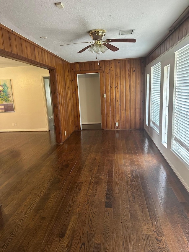 9337 Walterville Rd, Houston, TX 77080 - spare room with dark wood finished floors, a ceiling fan, a textured ceiling, and wood walls