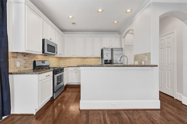 1320 Studer St, Houston, TX 77007 - kitchen with stainless steel appliances, arched walkways, dark stone countertops, white cabinets, and dark wood-type flooring