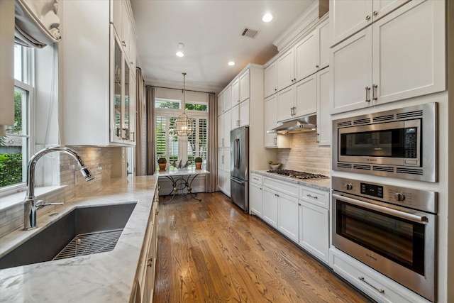 1126 Lake Pointe Pkwy, Sugar Land, TX 77478 - kitchen featuring appliances with stainless steel finishes, under cabinet range hood, recessed lighting, glass insert cabinets, and white cabinetry