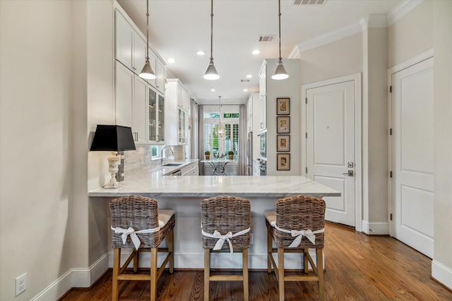1126 Lake Pointe Pkwy, Sugar Land, TX 77478 - kitchen with white cabinetry, a peninsula, glass insert cabinets, a breakfast bar, and crown molding