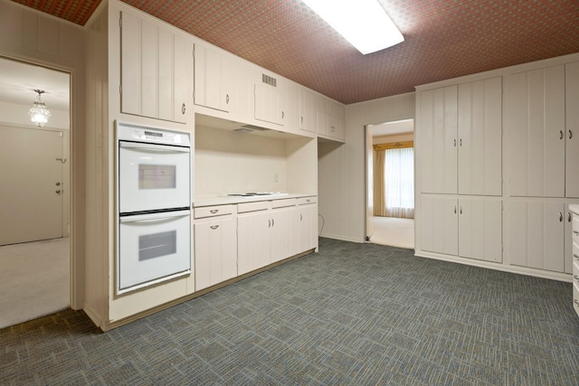 303 S Jackson St, Alvin, TX 77511 - kitchen with double oven, dark colored carpet, light countertops, and white cabinetry