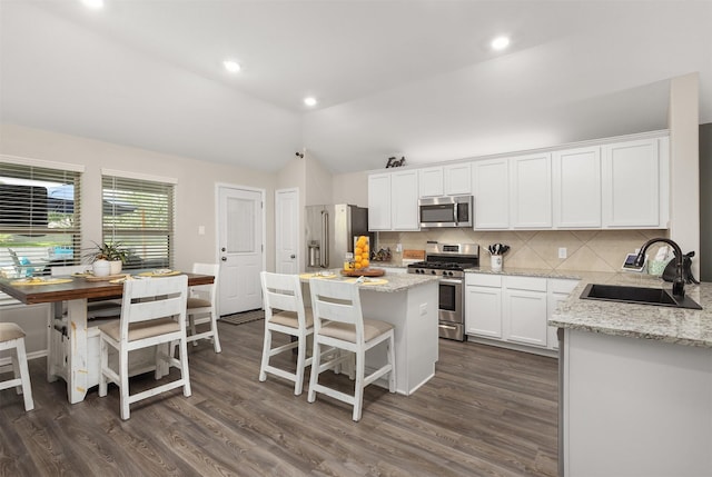 3051 Newcastle Crest Ln, Dickinson, TX 77539 - kitchen featuring appliances with stainless steel finishes, vaulted ceiling, white cabinetry, backsplash, and dark wood-type flooring