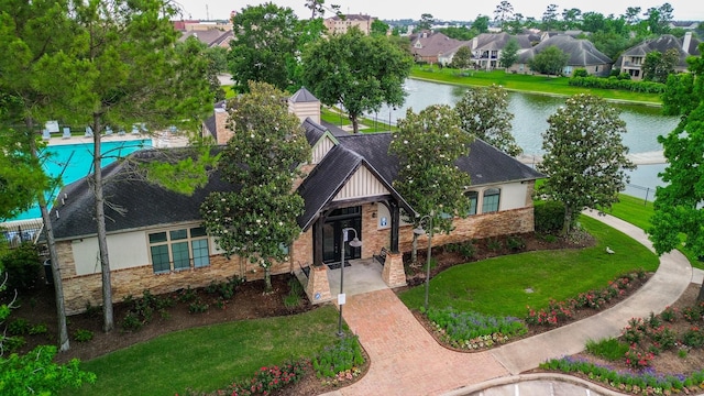 4723 Peninsula Garden Way, Humble, TX 77396 - view of front of house featuring a water view, a front lawn, roof with shingles, and stone siding