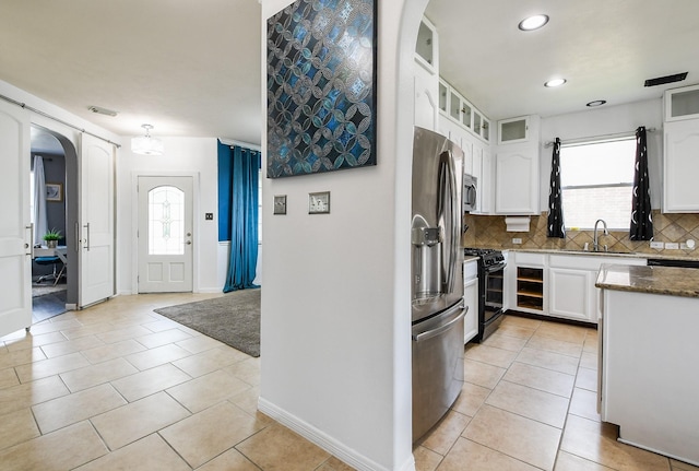 4723 Peninsula Garden Way, Humble, TX 77396 - kitchen with appliances with stainless steel finishes, arched walkways, white cabinetry, backsplash, and plenty of natural light
