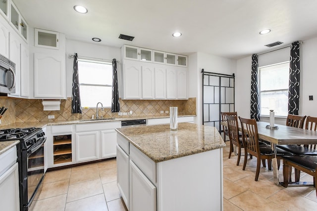 4723 Peninsula Garden Way, Humble, TX 77396 - kitchen with black gas stove, a center island, decorative backsplash, recessed lighting, and light tile patterned flooring