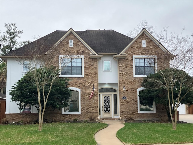 114 Arrowhead Dr, Lake Jackson, TX 77566 - traditional-style home featuring a front lawn, roof with shingles, brick siding, and stucco siding
