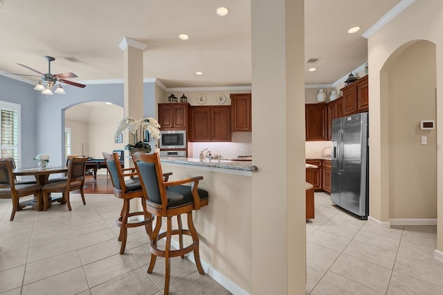 13603 Sand Mountain Ln, Houston, TX 77044 - kitchen featuring stainless steel appliances, arched walkways, ornamental molding, a breakfast bar, and light tile patterned flooring