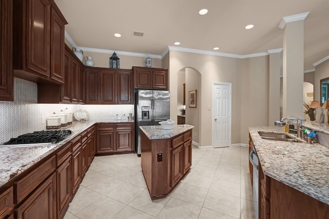 13603 Sand Mountain Ln, Houston, TX 77044 - kitchen with appliances with stainless steel finishes, arched walkways, ornamental molding, decorative backsplash, and a center island