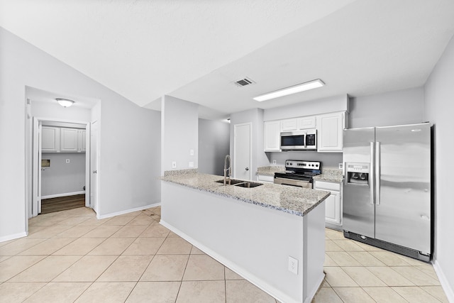 1617 Pecan Hollow St, Pearland, TX 77581 - kitchen featuring stainless steel appliances, light tile patterned floors, white cabinetry, light stone counters, and a peninsula