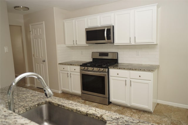 2434 Ranch Hollow Ct, Katy, TX 77494 - kitchen with appliances with stainless steel finishes, tasteful backsplash, white cabinetry, light stone countertops, and light tile patterned floors
