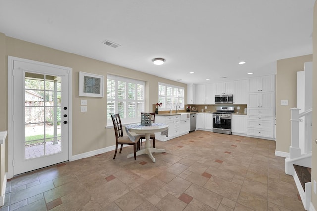 46 Lightwood Trce, The Woodlands, TX 77382 - kitchen with appliances with stainless steel finishes, white cabinets, recessed lighting, light stone finish flooring, and light countertops
