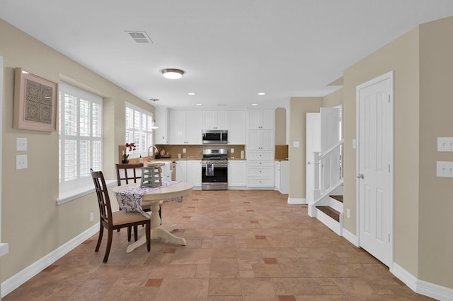 46 Lightwood Trce, The Woodlands, TX 77382 - kitchen featuring stainless steel appliances, white cabinets, light countertops, stone finish flooring, and recessed lighting