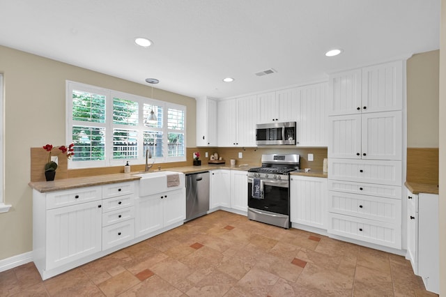 46 Lightwood Trce, The Woodlands, TX 77382 - kitchen with stainless steel appliances, white cabinets, recessed lighting, and hanging light fixtures