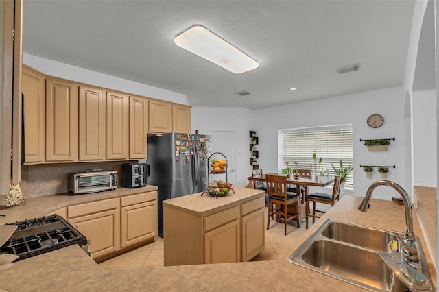 7710 Aerobic Ave, Humble, TX 77346 - kitchen featuring gas range, light brown cabinetry, light countertops, light tile patterned flooring, and freestanding refrigerator