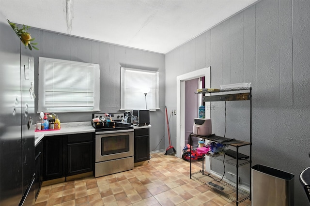 208 S Cloud St, Wharton, TX 77488 - kitchen with electric stove, dark cabinets, light countertops, and wood walls