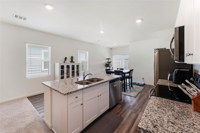 10138 California Lily Ln, Houston, TX 77016 - kitchen featuring stainless steel appliances, white cabinetry, light stone counters, a kitchen island with sink, and dark wood finished floors
