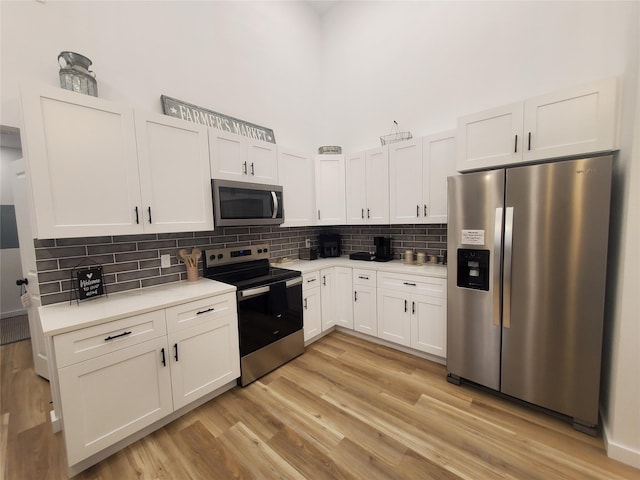 95 Red Tip Ln, Brenham, TX 77833 - kitchen with appliances with stainless steel finishes, light countertops, tasteful backsplash, light wood finished floors, and white cabinets