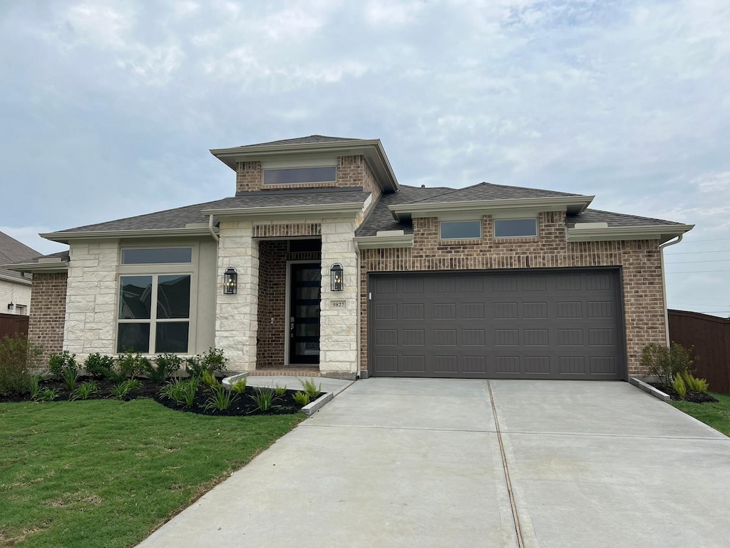 9827 Starry Night Ln, Manvel, TX 77578 - prairie-style house featuring driveway, a garage, a front lawn, and a shingled roof