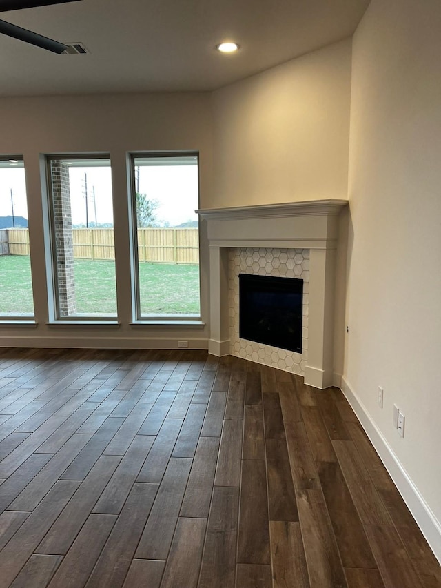 9827 Starry Night Ln, Manvel, TX 77578 - unfurnished living room featuring dark wood-type flooring, plenty of natural light, a tiled fireplace, and recessed lighting