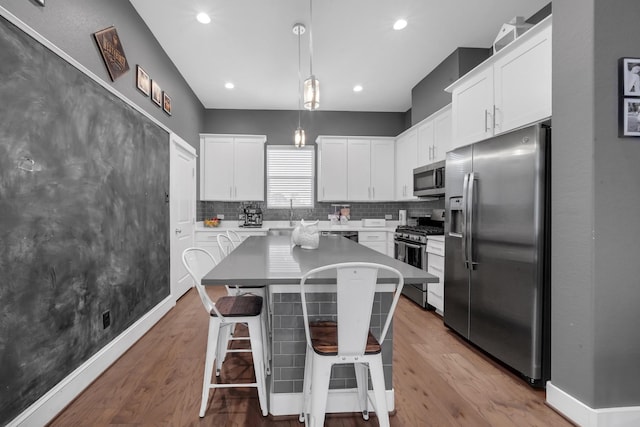 734 W Donovan St, Houston, TX 77091 - kitchen featuring appliances with stainless steel finishes, tasteful backsplash, a kitchen bar, white cabinets, and a kitchen island
