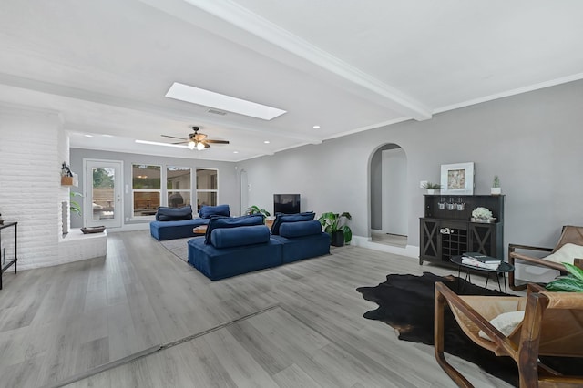 7530 Deep Forest Dr, Houston, TX 77088 - living area featuring arched walkways, ceiling fan, light wood-style flooring, a skylight, and beamed ceiling