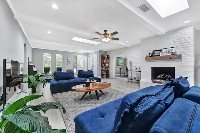 7530 Deep Forest Dr, Houston, TX 77088 - living area with a skylight, beam ceiling, arched walkways, wood finished floors, and a fireplace