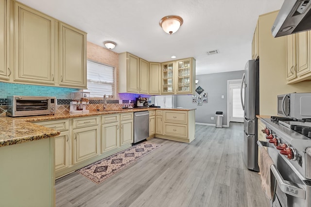 7530 Deep Forest Dr, Houston, TX 77088 - kitchen featuring cream cabinetry, appliances with stainless steel finishes, and ventilation hood