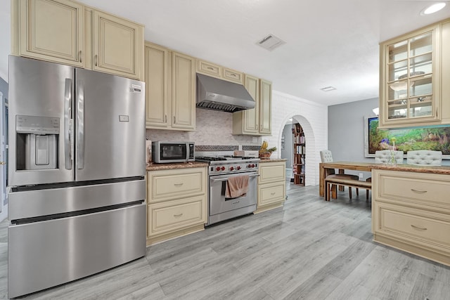 7530 Deep Forest Dr, Houston, TX 77088 - kitchen with cream cabinets, stainless steel appliances, ventilation hood, and arched walkways