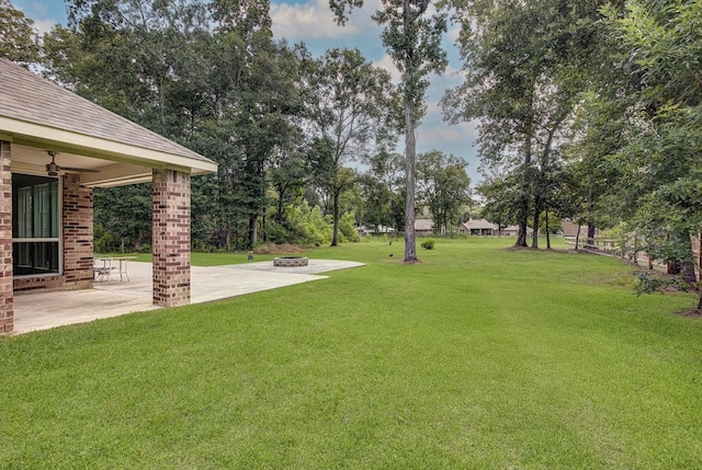 285 Rd 66121, Dayton, TX 77535 - view of grassy yard featuring a patio area, a ceiling fan, an outdoor fire pit, and view of scattered trees