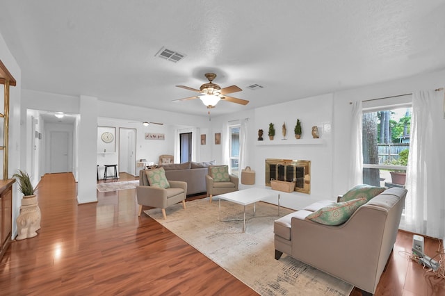 27237 Lana Ln, Conroe, TX 77385 - living room featuring wood finished floors, ceiling fan, and a glass covered fireplace