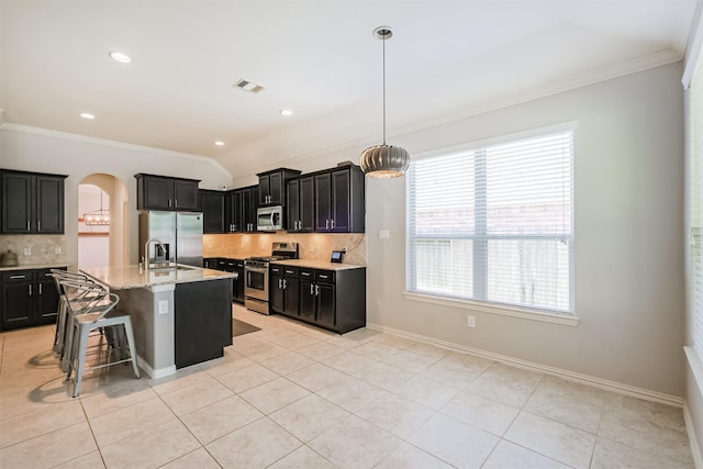 18002 Quarry Vale Dr, Cypress, TX 77429 - kitchen featuring stainless steel appliances, crown molding, dark cabinets, arched walkways, and tasteful backsplash