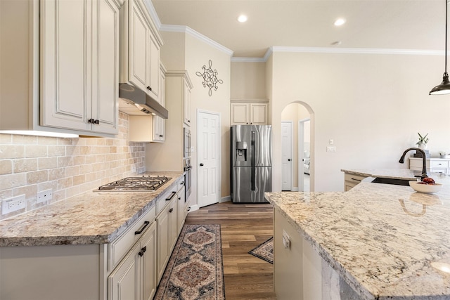 12015 Obsidian Ln, Dayton, TX 77535 - kitchen featuring appliances with stainless steel finishes, arched walkways, ornamental molding, under cabinet range hood, and tasteful backsplash