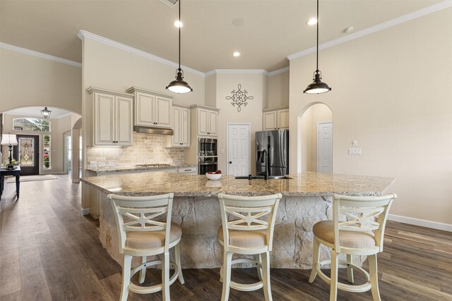 12015 Obsidian Ln, Dayton, TX 77535 - kitchen with appliances with stainless steel finishes, cream cabinets, arched walkways, decorative backsplash, and a towering ceiling