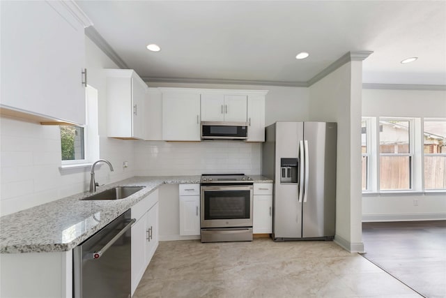 102 Glendale St, Houston, TX 77012 - kitchen featuring appliances with stainless steel finishes, white cabinetry, light stone countertops, backsplash, and crown molding