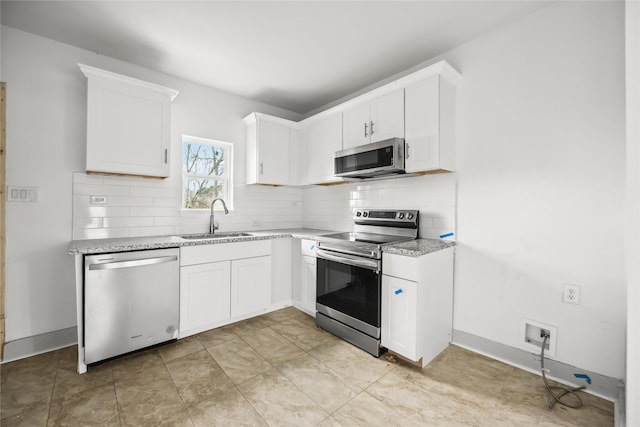 102 Glendale St, Houston, TX 77012 - kitchen featuring appliances with stainless steel finishes, backsplash, white cabinetry, and light stone countertops